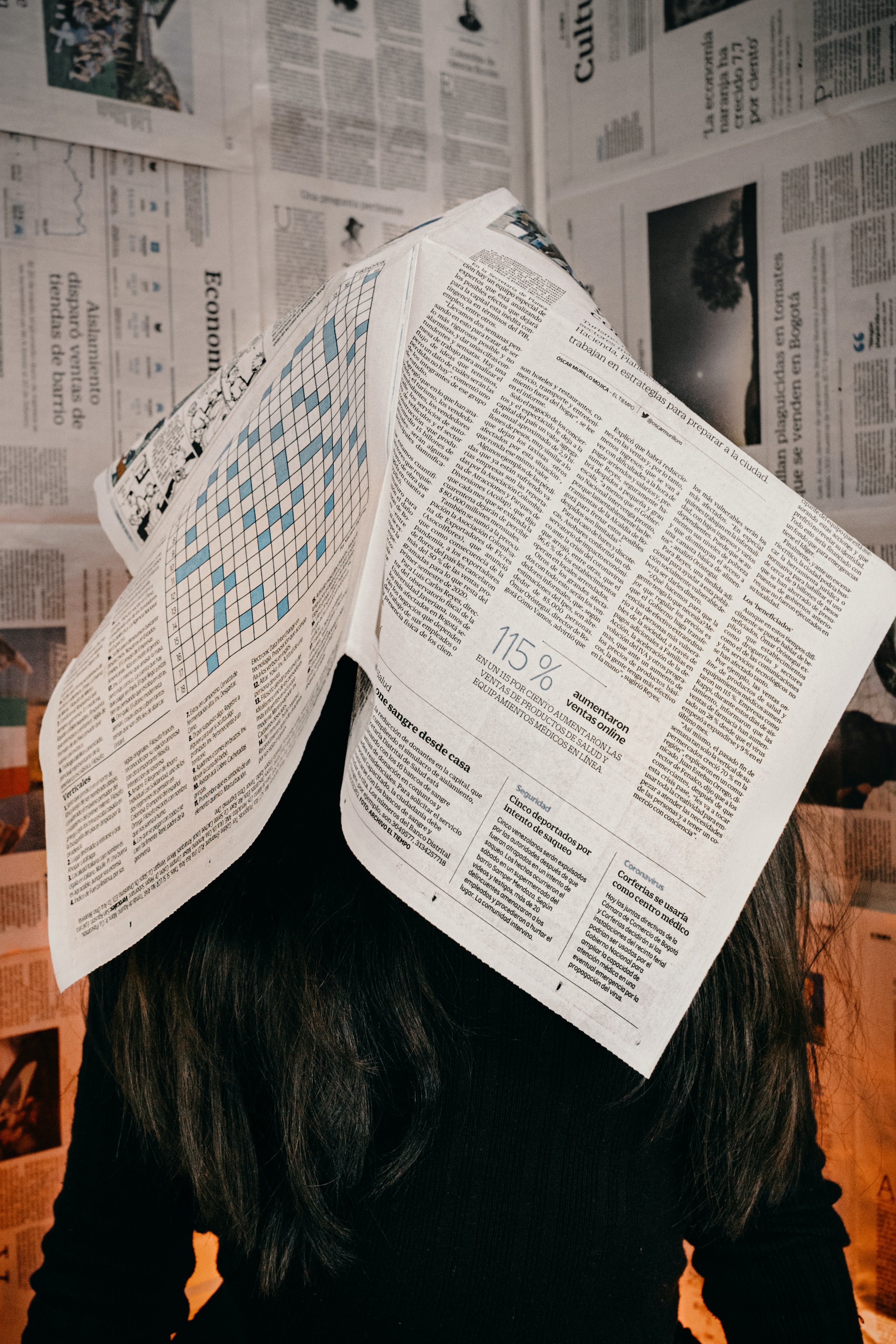 Photo of a woman with a newspaper over her head.